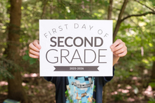 Load image into Gallery viewer, Person holding a sign for the 'First Day of Second Grade' in a forest setting