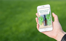 Load image into Gallery viewer, woman holding phone with ebook - essential oils for repelling bugs - green grass background