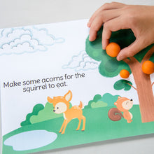 Load image into Gallery viewer, child&#39;s hand holding orange playdough ball on printed page
