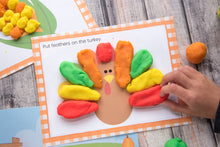 Load image into Gallery viewer, child playing with colorful playdough turkey for thanksgiving - printable mats on wood background
