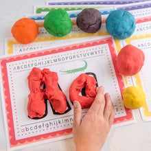 Load image into Gallery viewer, child making play dough alphabet with letters playdough mats and colorful balls of playdoh
