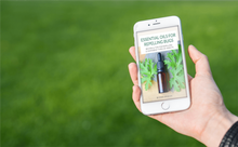 Load image into Gallery viewer, woman holding phone with ebook - essential oils for repelling bugs - green grass background

